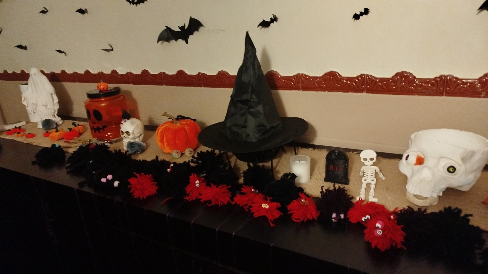 Prateleira decorada com chapéu de bruxa, caveira, abóbora e morcegos